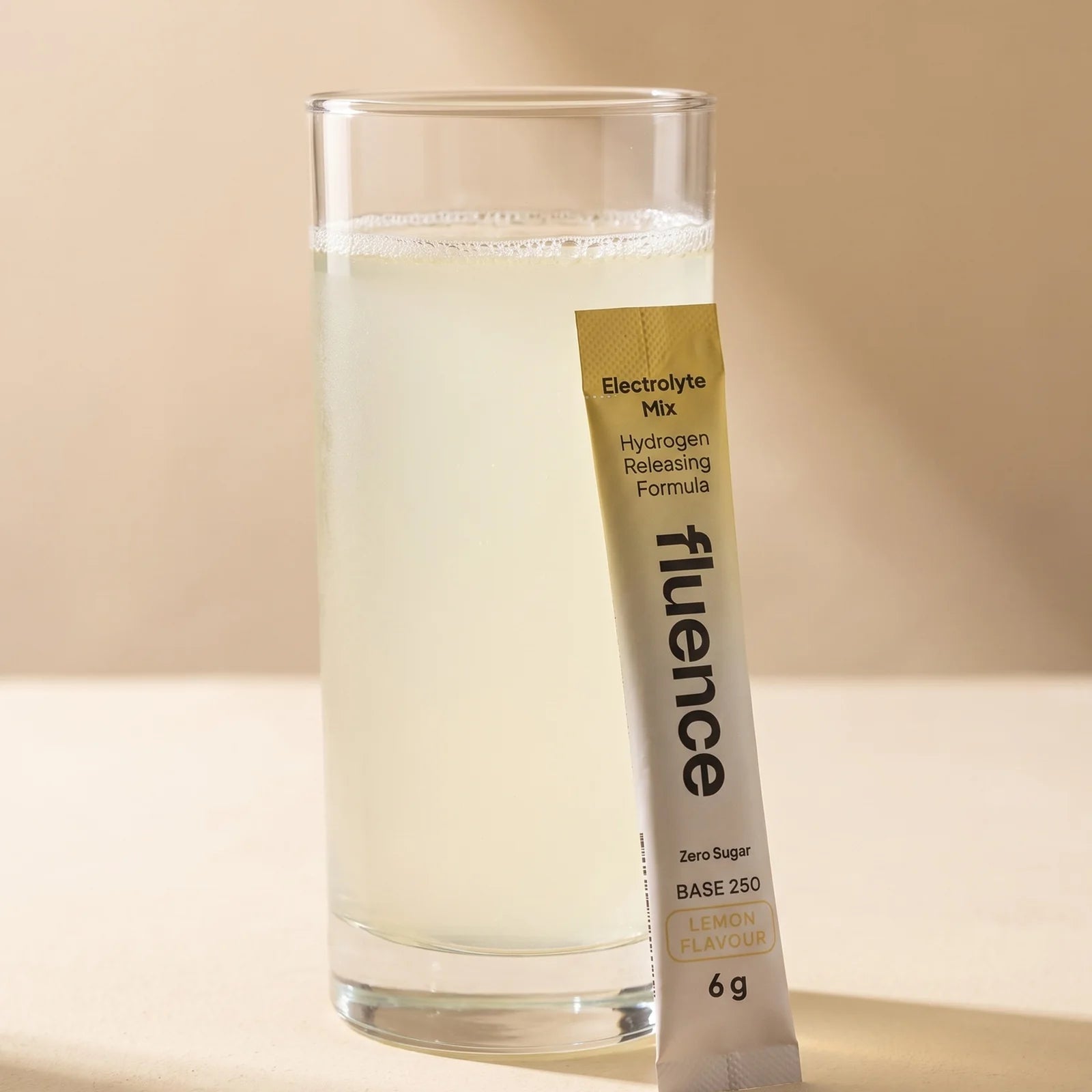 A glass of Base 250 Lemon beside a Lemon sachet
