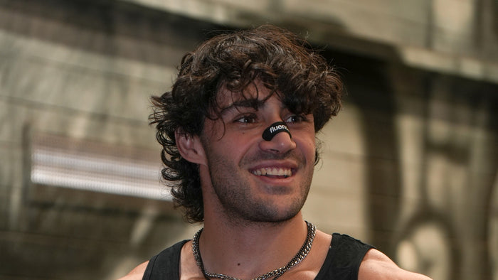 Man wearing a black Fluence performance nasal strip across the bridge of his nose in a gym