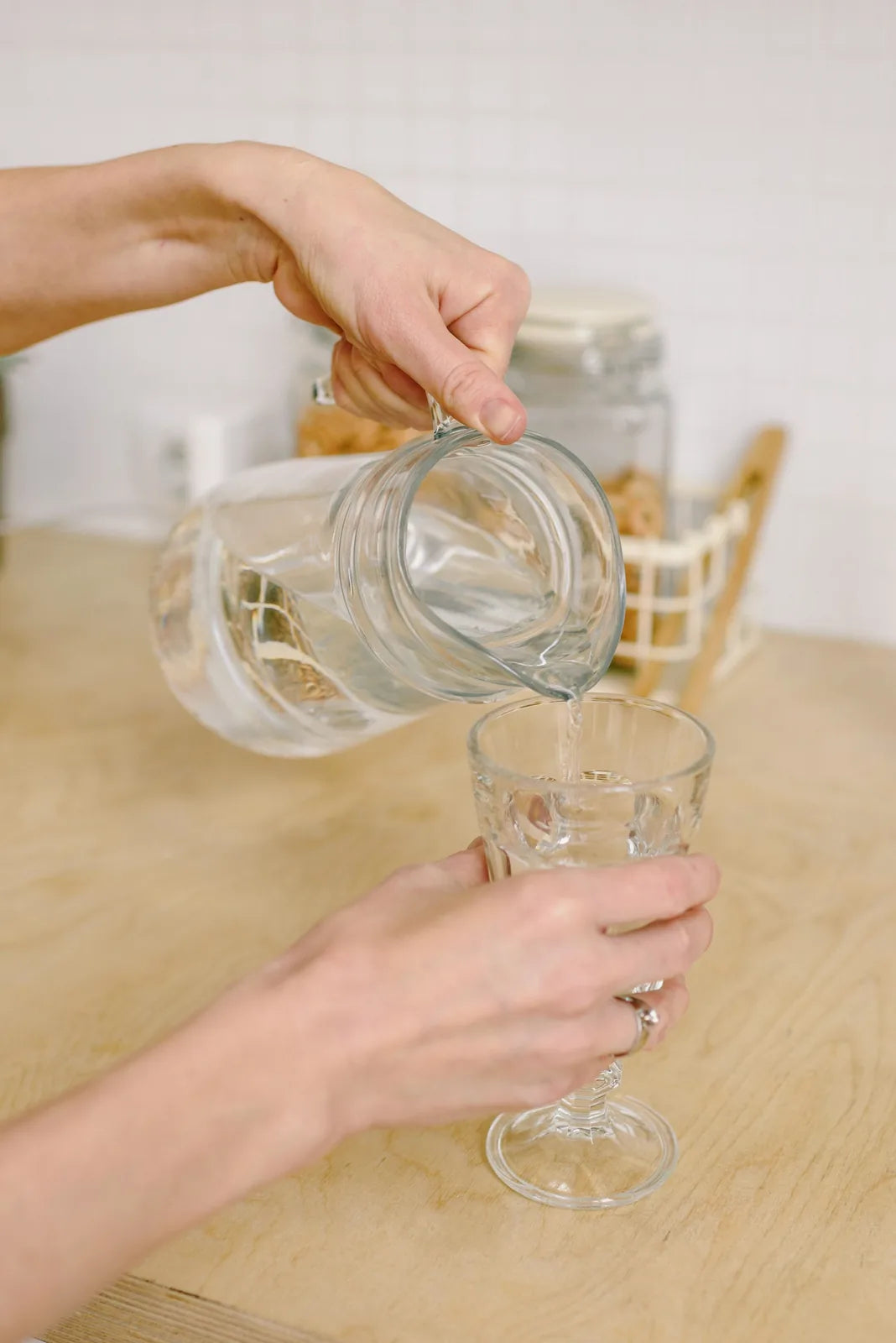 Water being poured into a glass on a kitchen bench