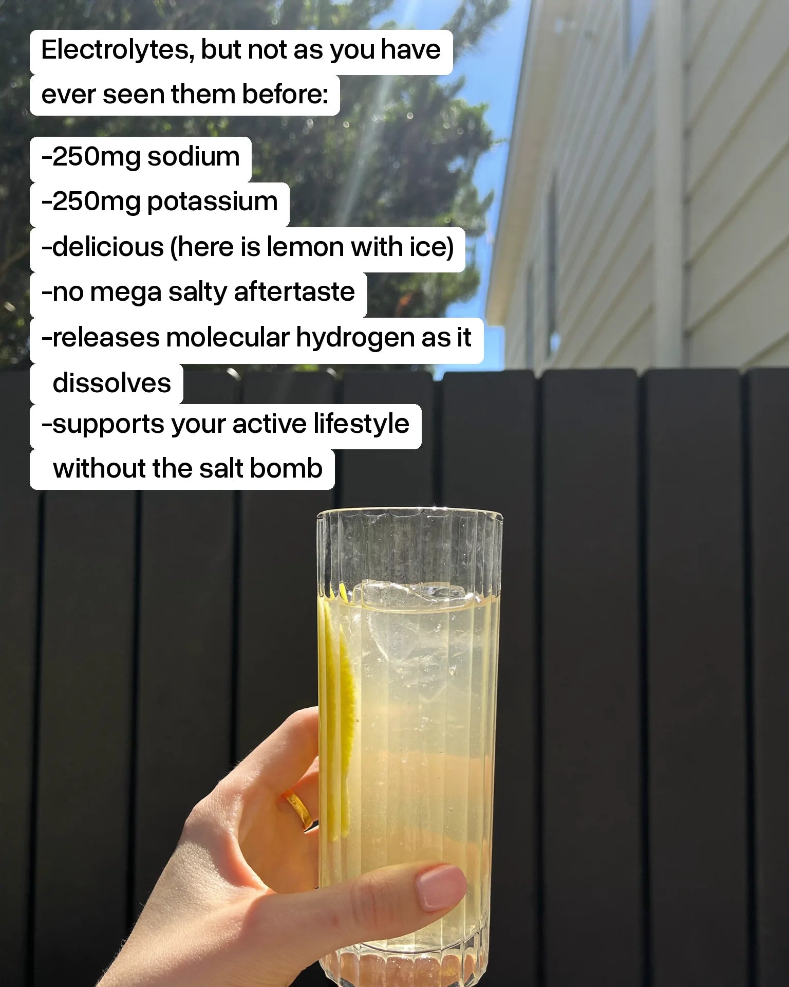 A glass of Base 250 Lemon with ice, held up in the sun