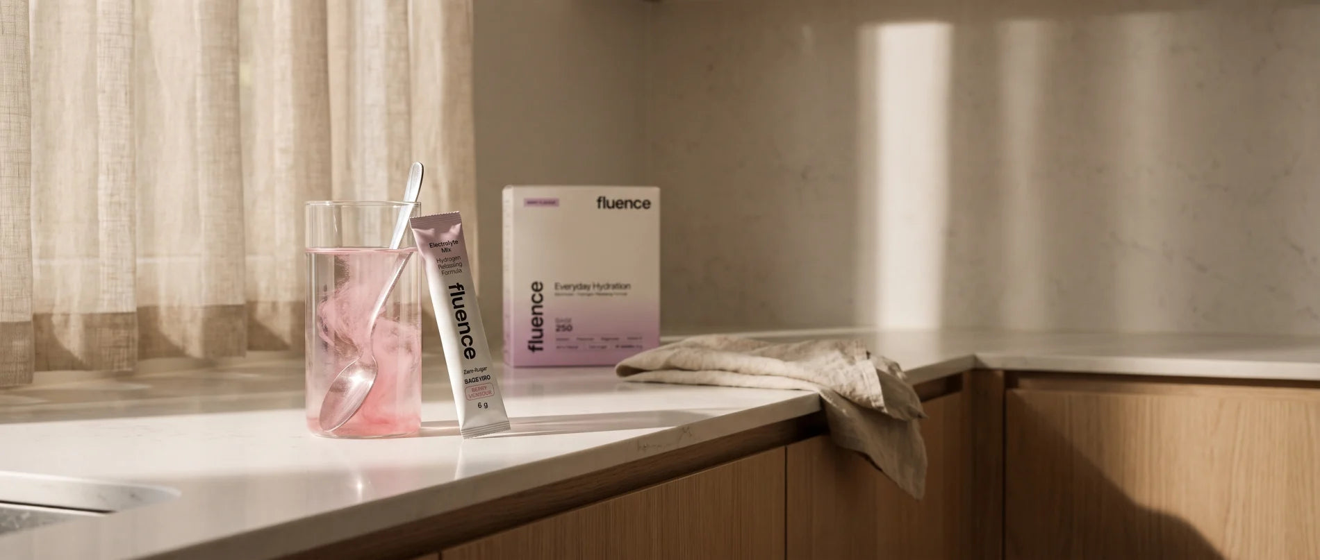 A glass of berry Base 250 with a sachet dissolving on a bright, calm kitchen counter