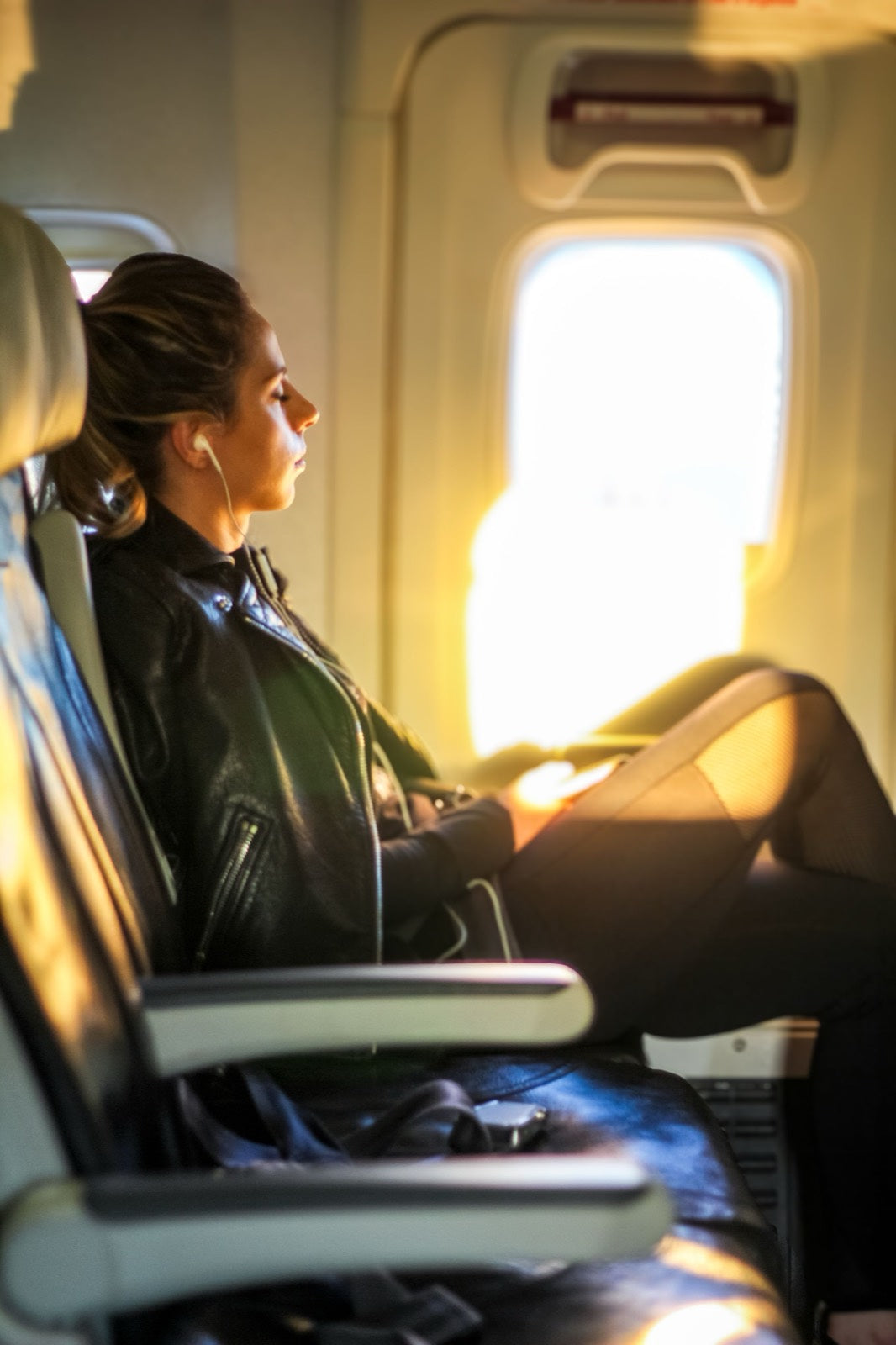 A passenger in a plane cabin seat in soft light