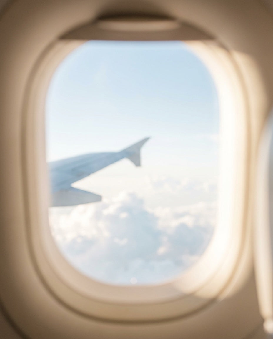 Wing and sky through a cabin window in soft light